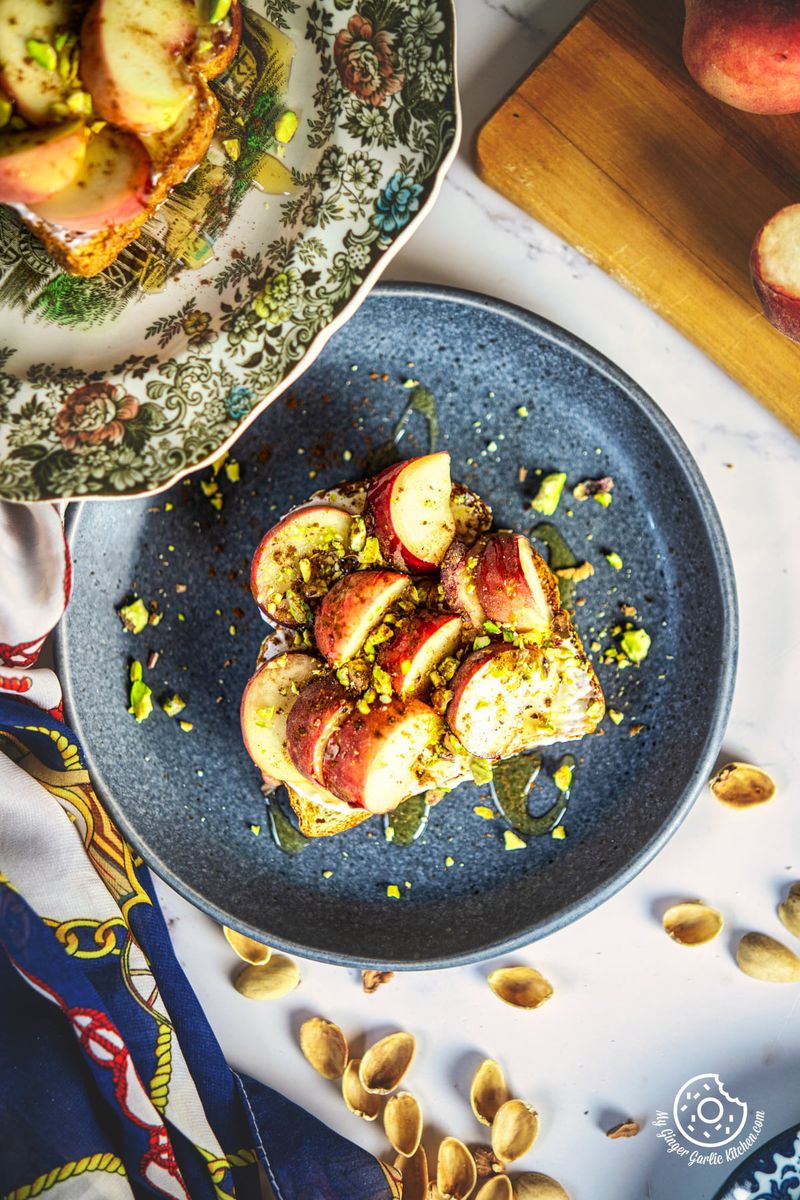 overhead photo of a plate of peach toast with a piece of bread and a bowl of fruit