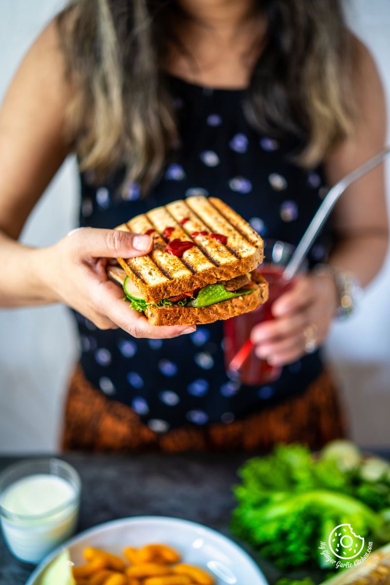a female holding peanut butter and veggie grilled cheese sandwich