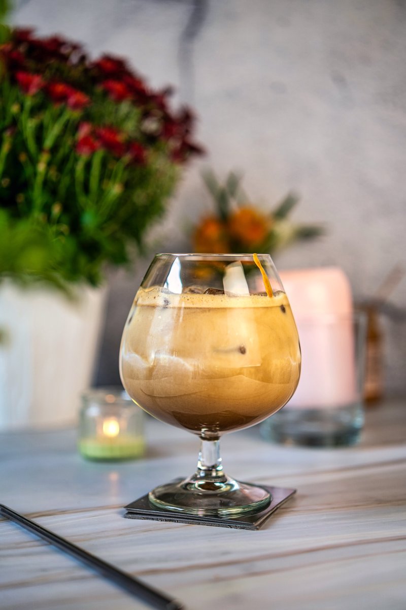 Creamy peanut butter iced latte served over ice in a stemmed glass