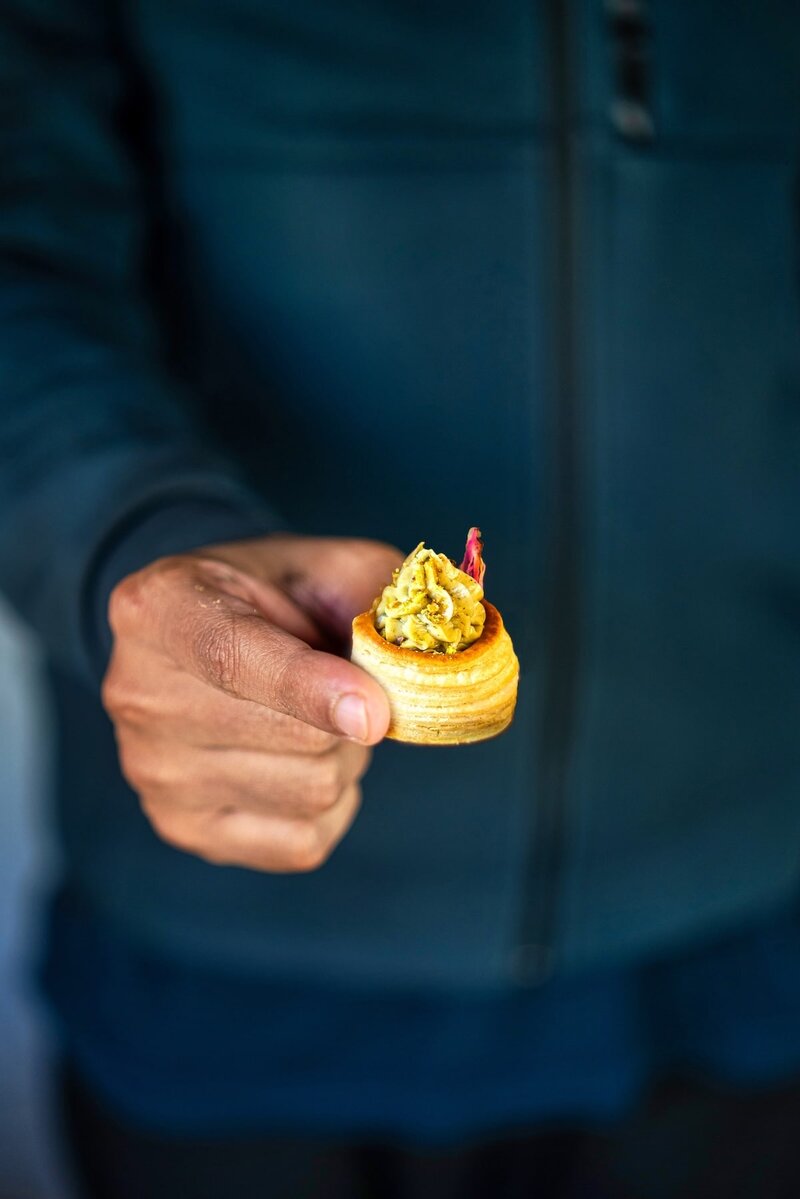 Close-up of a hand holding a no-bake pistachio cream cup dessert with golden pastry and creamy pistachio filling