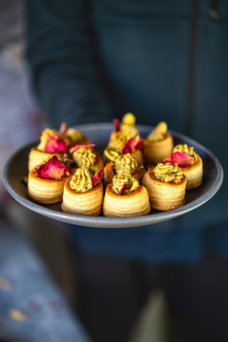 Tray of mini no-bake pistachio cream cups with rose petal garnish, perfect for party dessert recipes