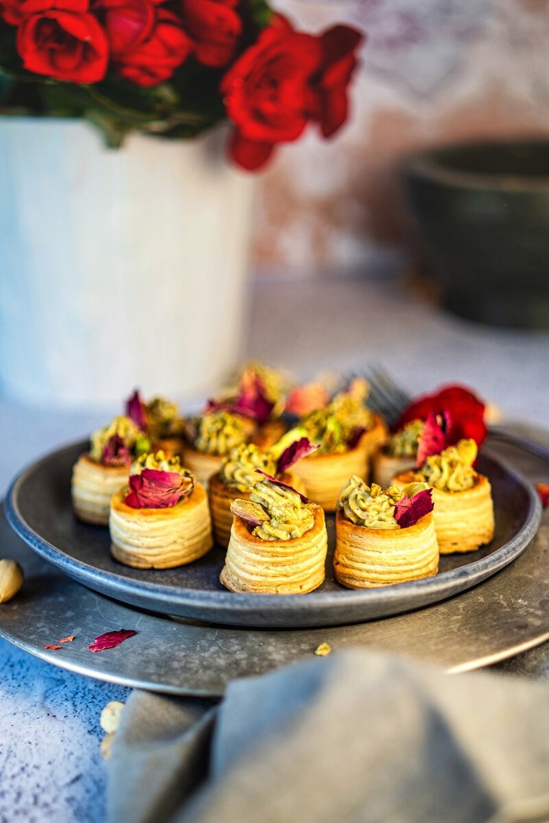 Plate of easy no-bake pistachio cream cups topped with pistachio cream and rose petals, ideal for festive parties