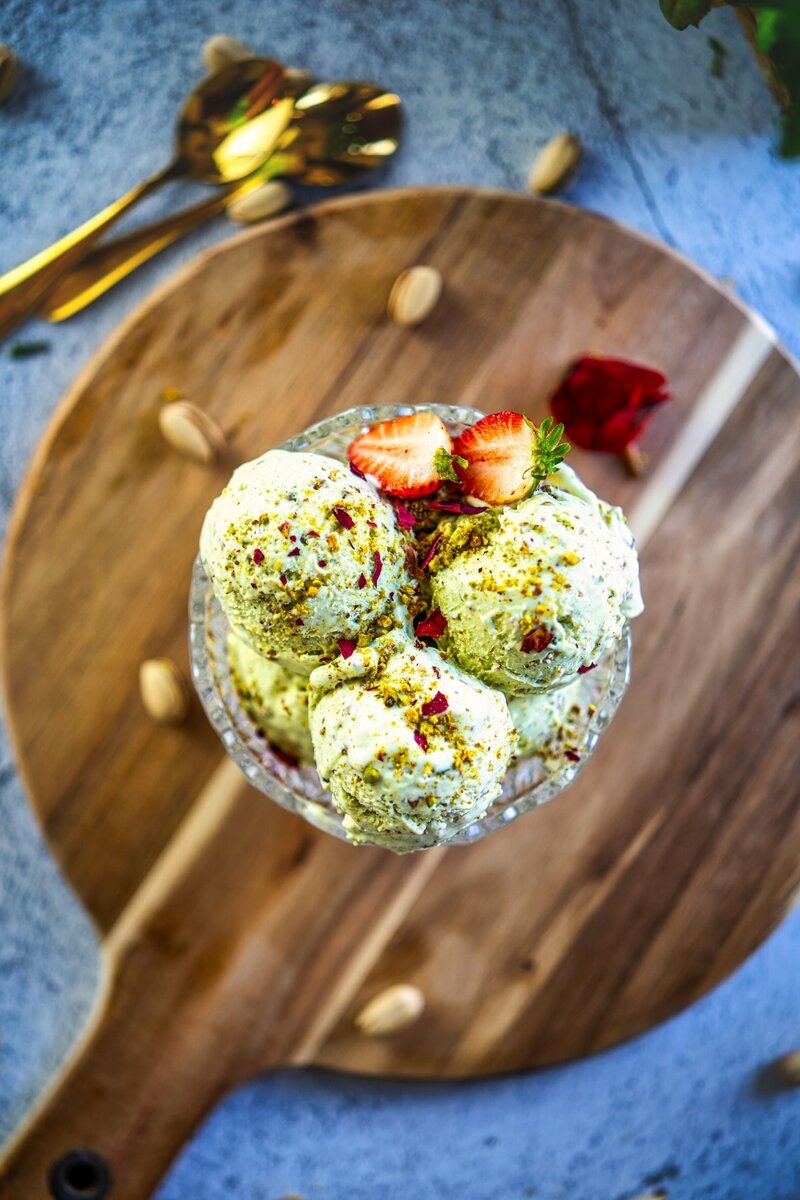 Person holding a bowl of homemade pistachio ice cream with crushed nuts, easy and creamy pistachio ice cream recipe