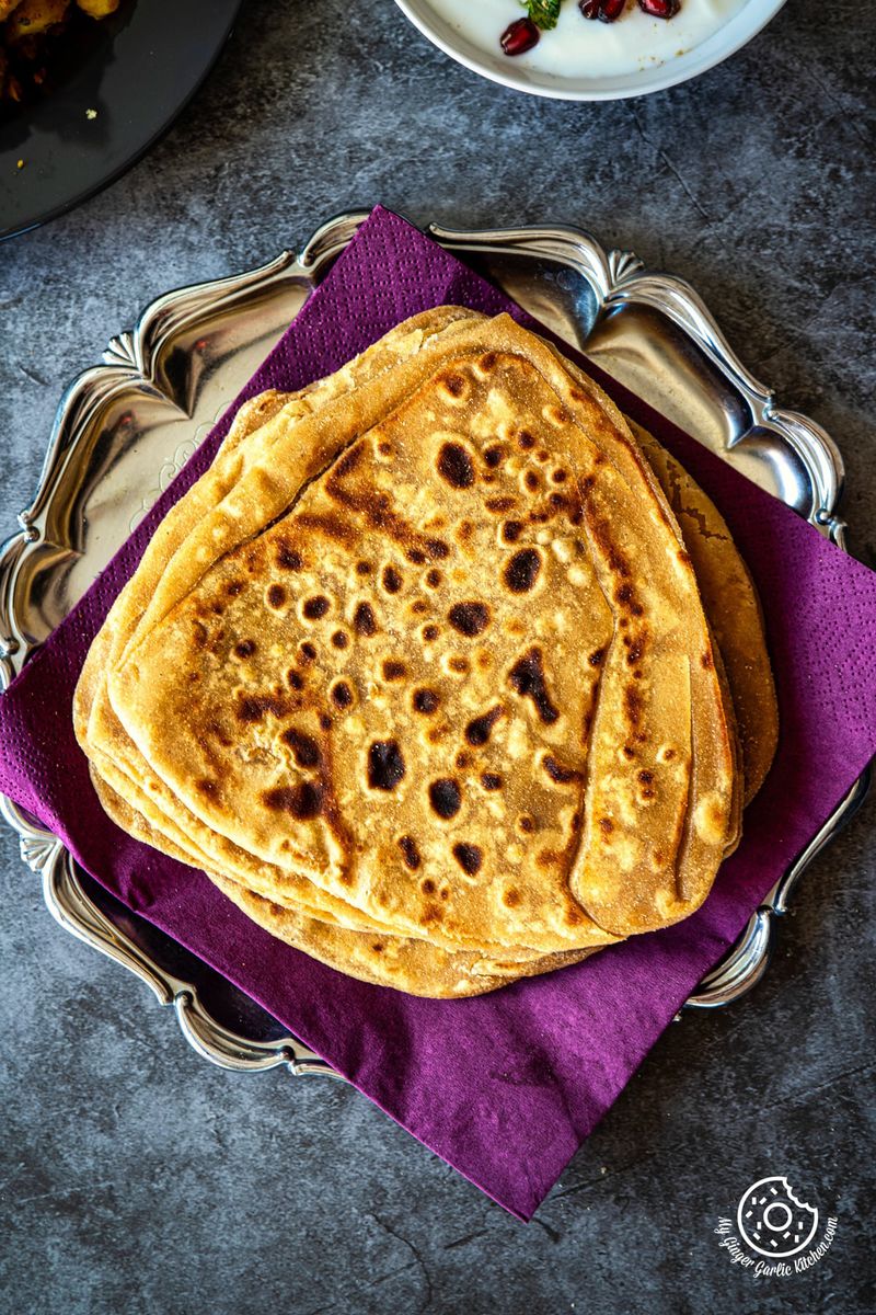 overhead photo of a plate of indian paratha flatbread on a purple napkin