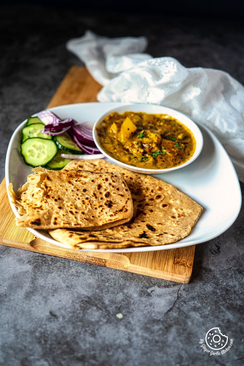 photo of a plate of plain paratha with a bowl of curry