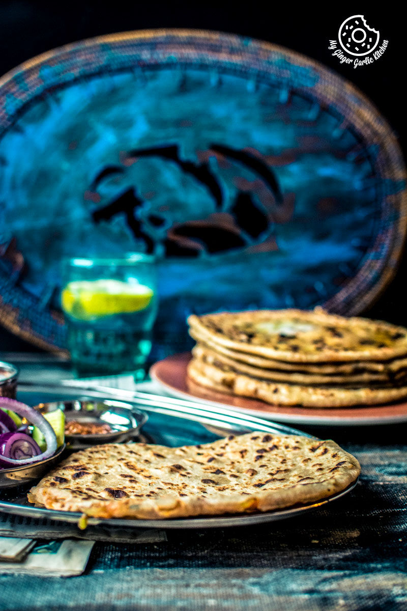 there are two plates of  tandoori aloo ka paratha on a table with a blue plate
