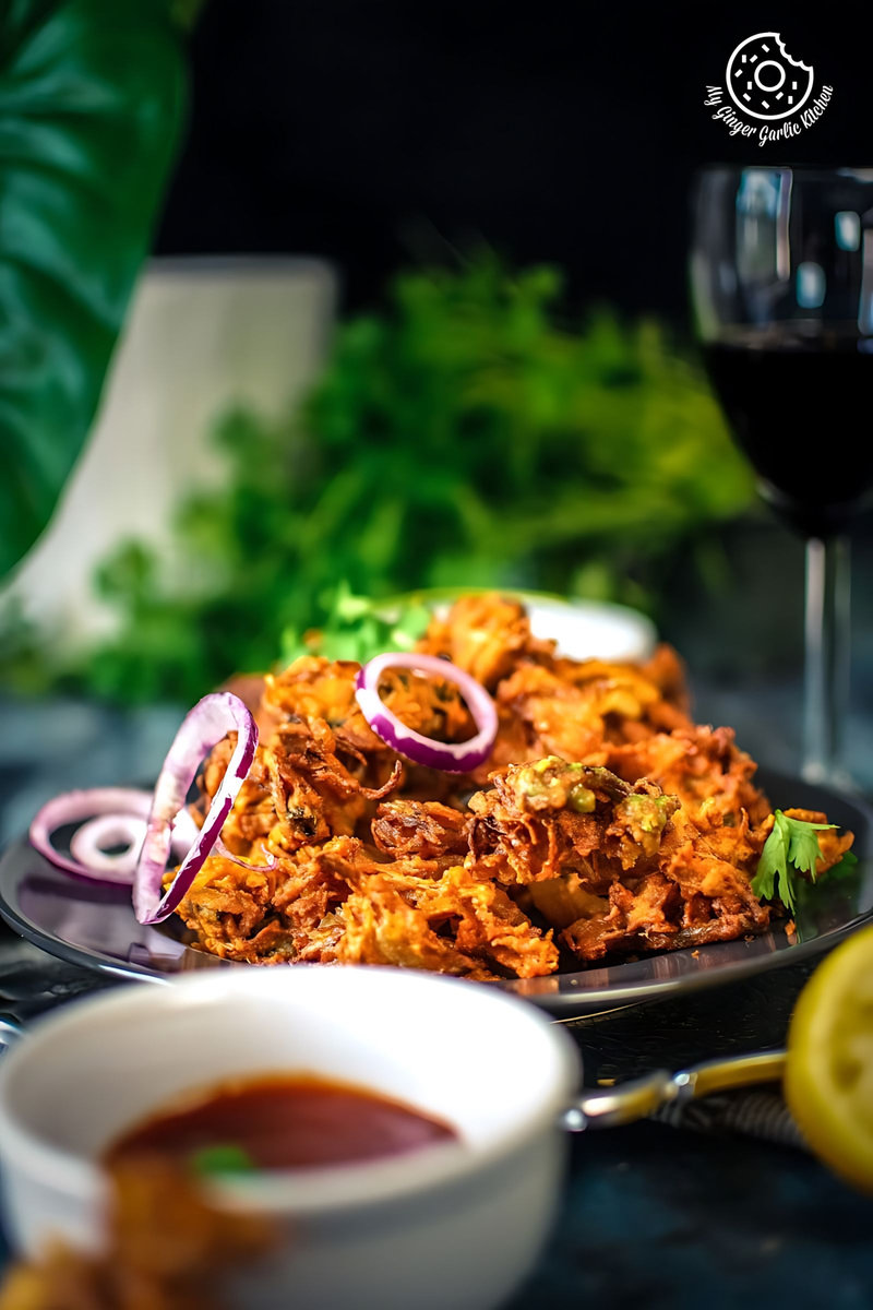 onion pakoda with purple onion rings and a wine glass in the backdrop