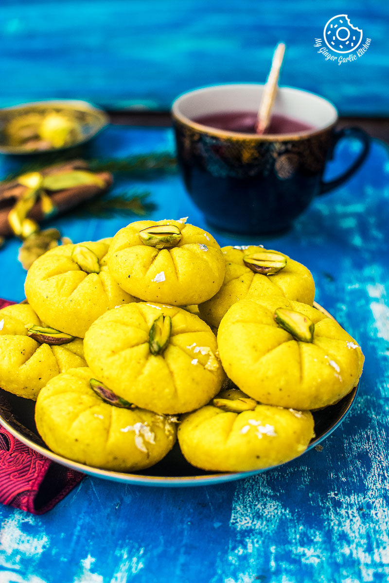 a plate of yellow kesar peda on a blue table