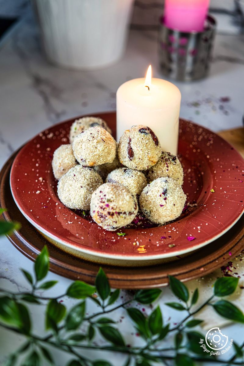photo of a plate of  Rava Laddu and a candle on a table