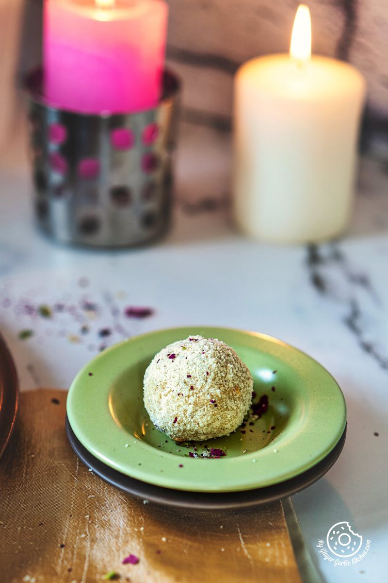 photo of a plate of one rava laddu with a candle in the background