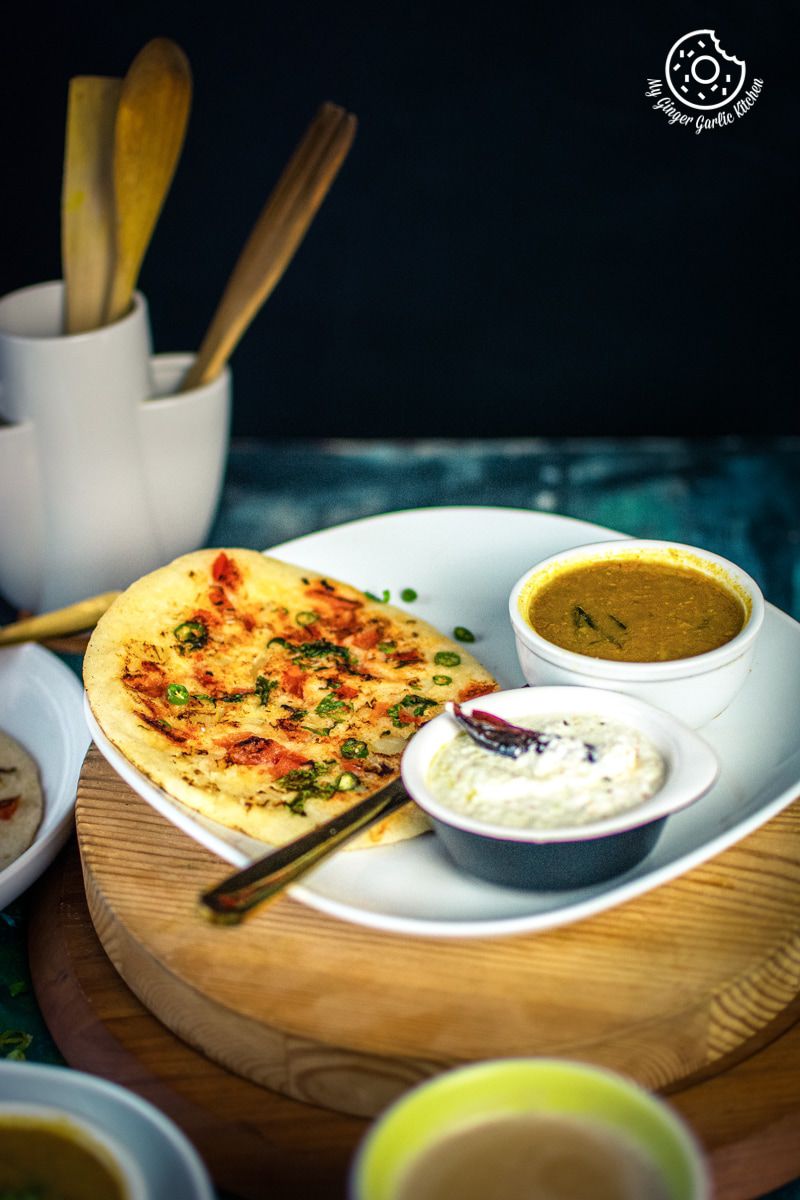 instant rava uttapam served in a white plate with sambar and coconut chutney