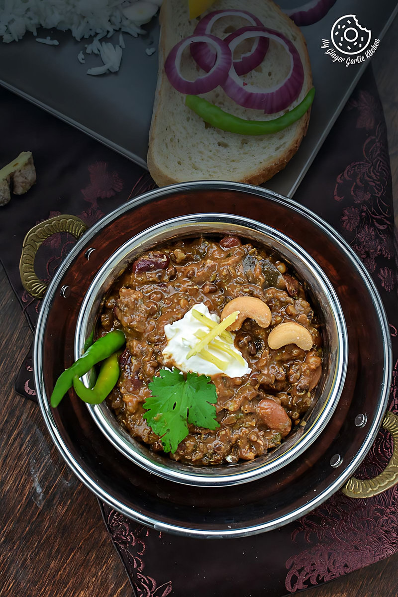 a bowl of three bean thick dal makhani with a spoon and some bread