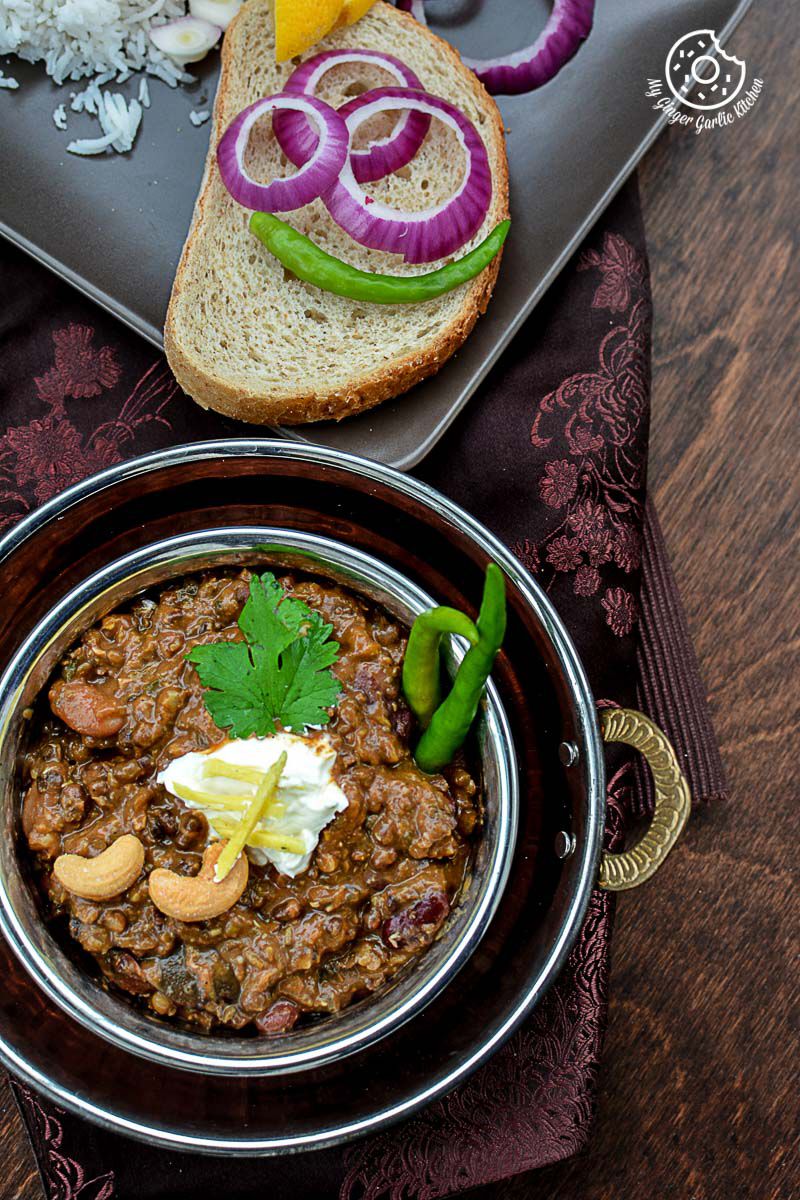 a bowl of three bean thick dal makhani and bread on a table