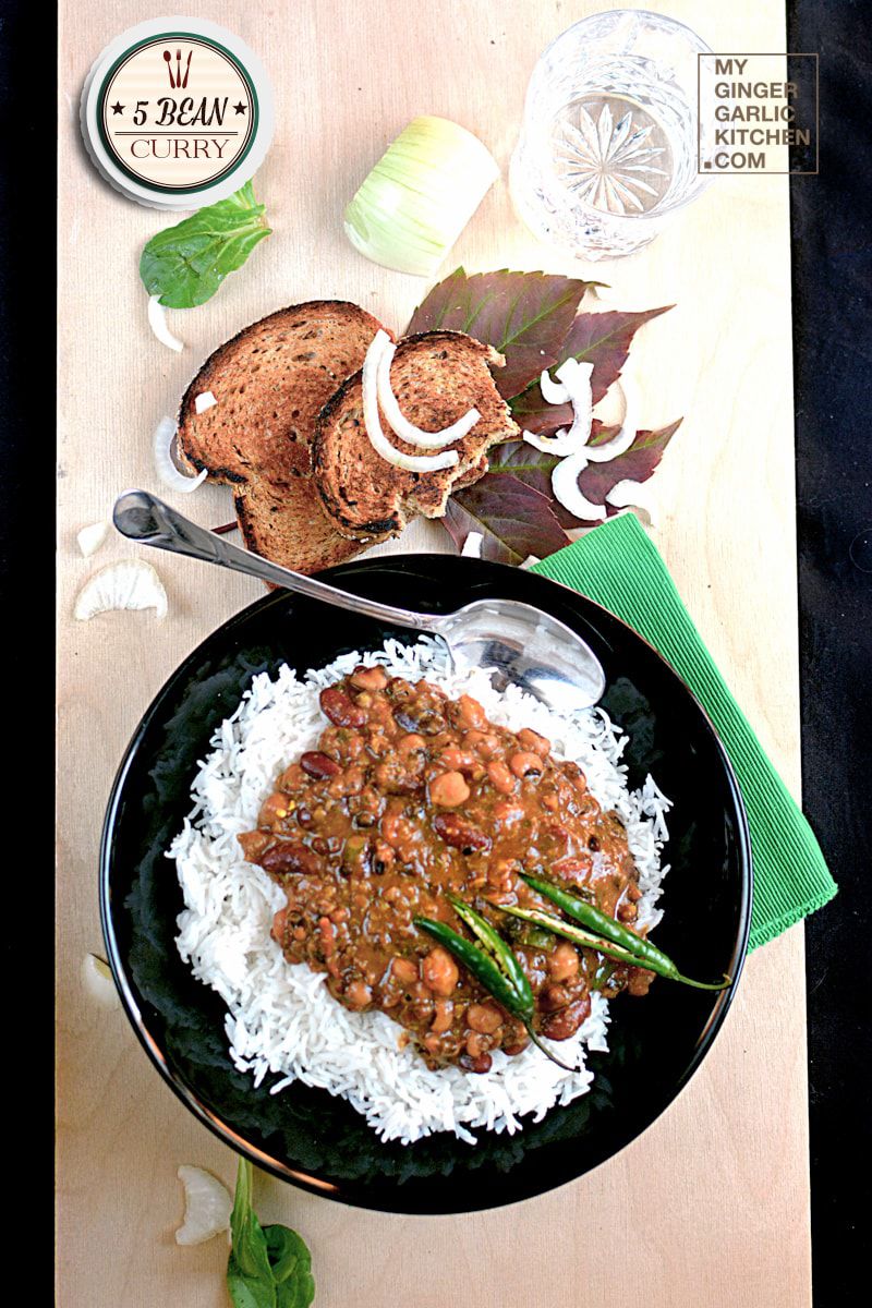 a bowl of 5 bean curry with rice and some toasted bread on a table on a table