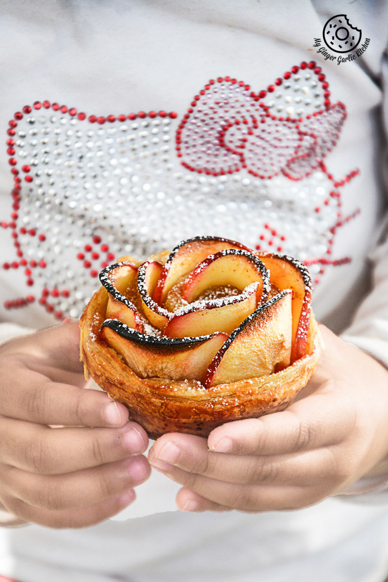 someone holding a apple rose mini tartlet in their hands