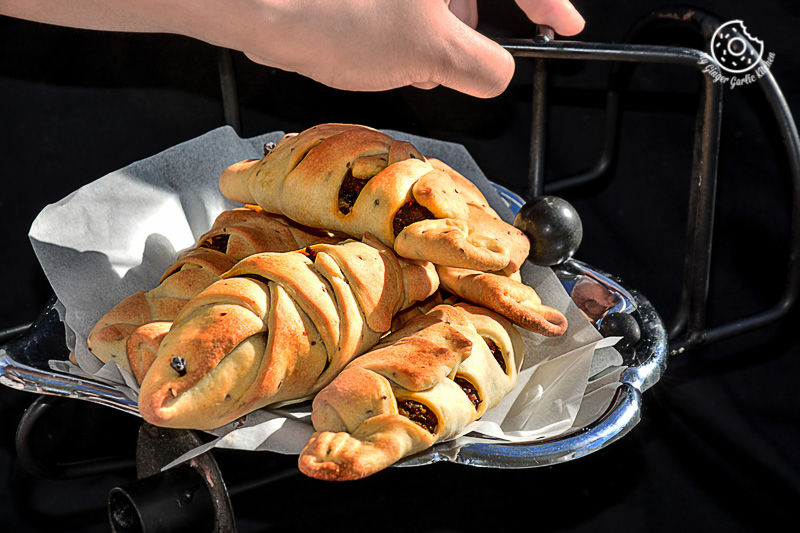 a basket of baked fish shaped samosa on a table with a person it