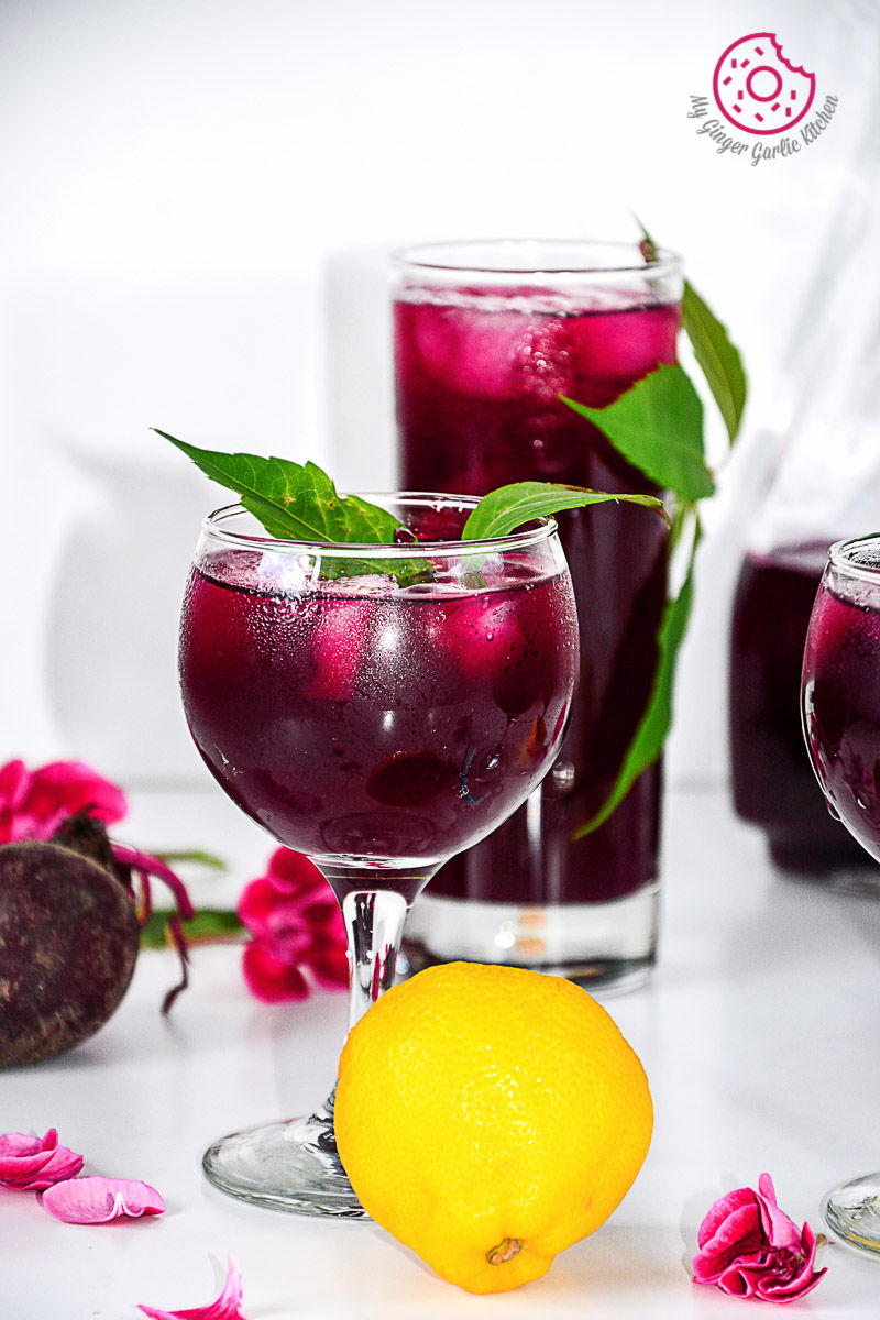 three glasses of beet lemonade with a lemon and a flower