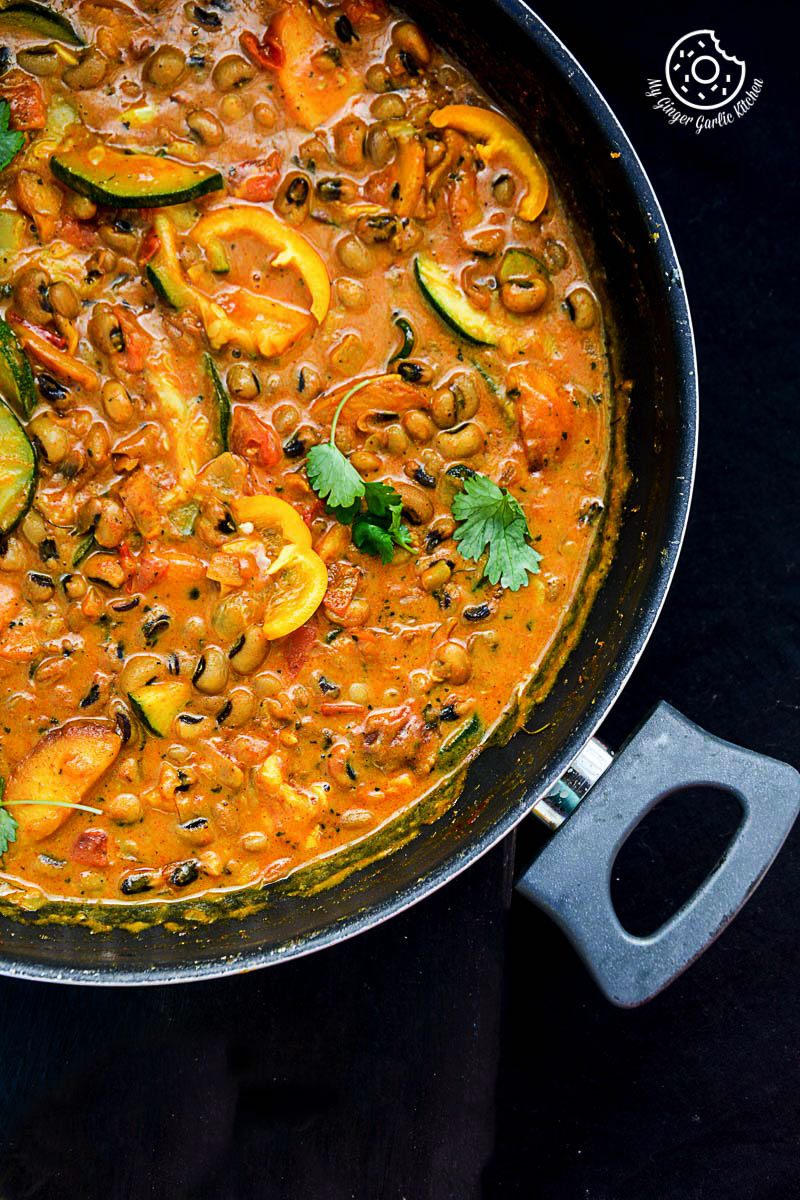 a pan of black eyed bean zucchini peach curry with on a table