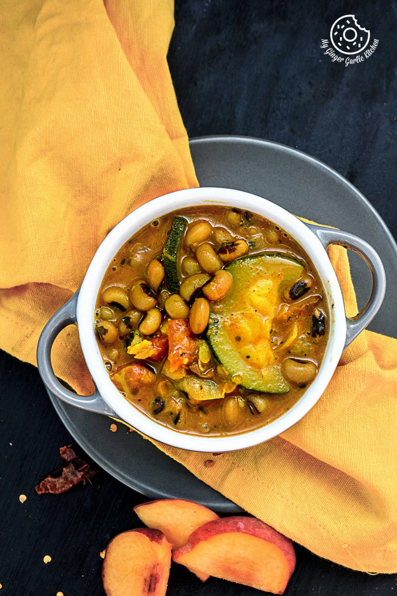 a bowl of black eyed bean zucchini peach curry with a yellow napkin