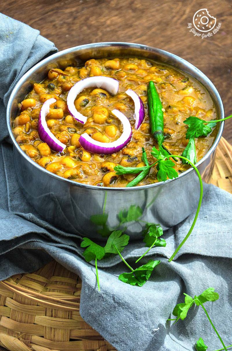 a bowl of black eyed pea curry in pepper onion gravy with onions and green green chili