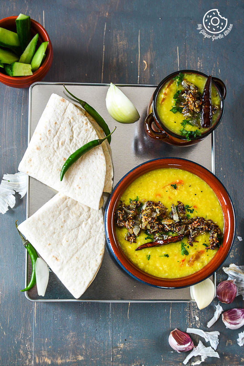 two bowls of cardamom scented moong dal tadka and a plate of tortillas on a table