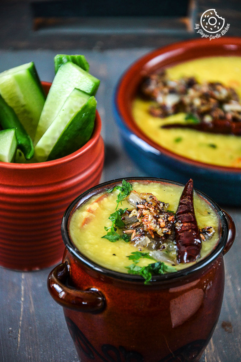 bowls of cardamom scented moong dal tadka and vegetables are sitting on a table