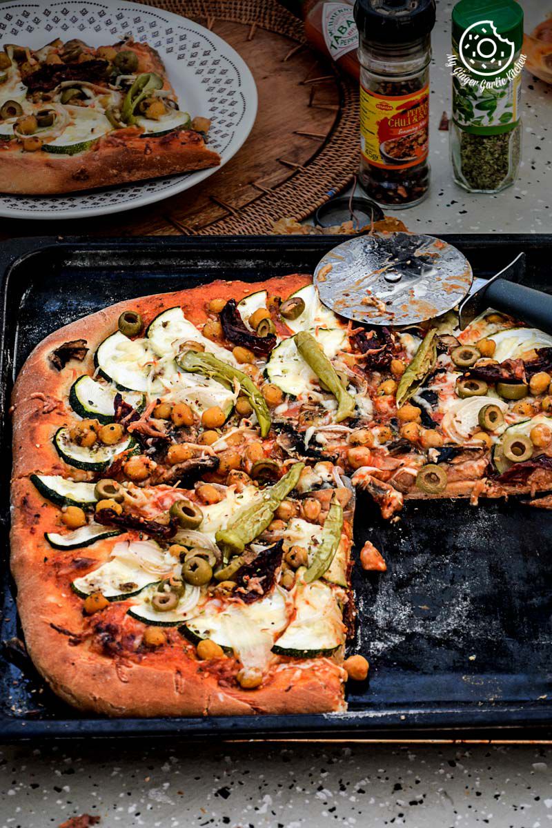 a chickpea zucchini mushroom pizza with and olives, and other toppings on a tray