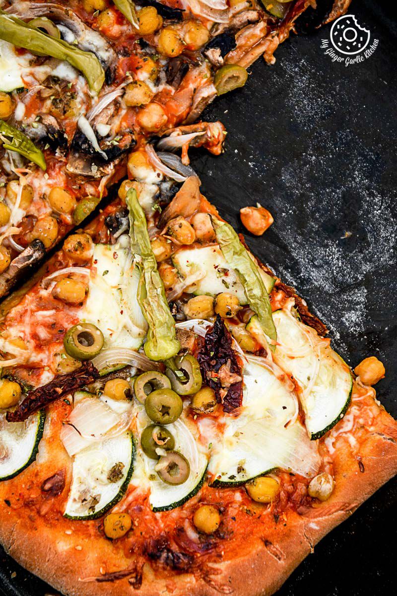chickpea zucchini mushroom pizza with pickled peppers and olives on it on a pan