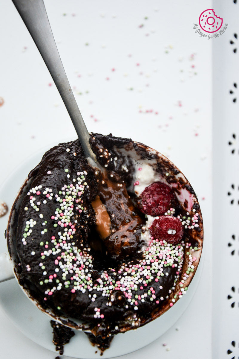 a chocolate molten lava mug cake with sprinkles and a spoon in it