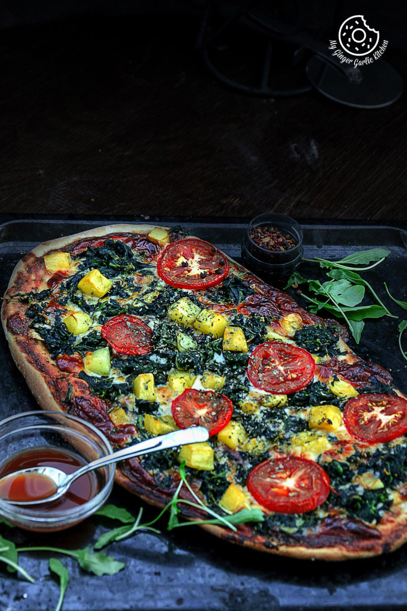 garlicky spinach mango tomato pizza on a tray
