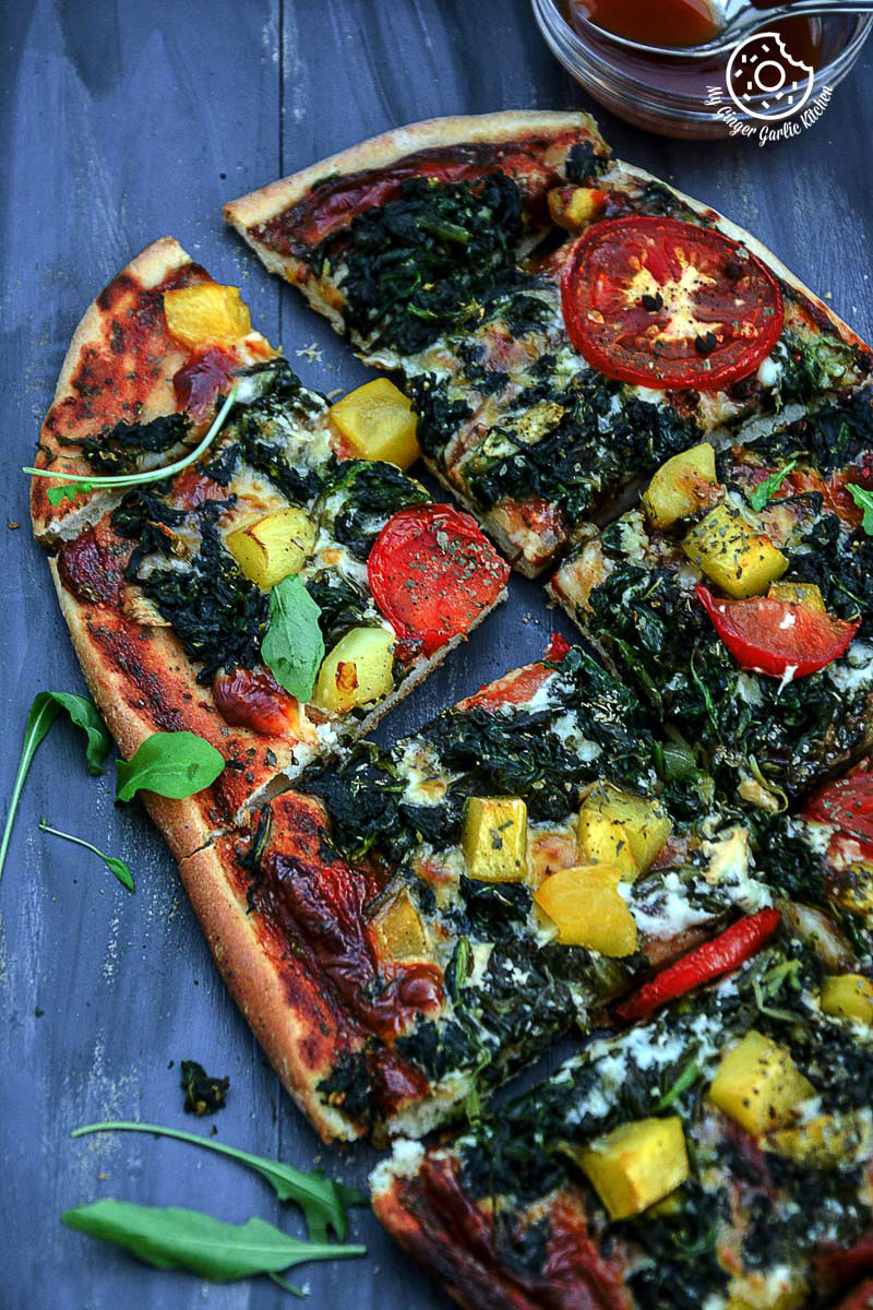 a garlicky spinach mango tomato pizza on a table