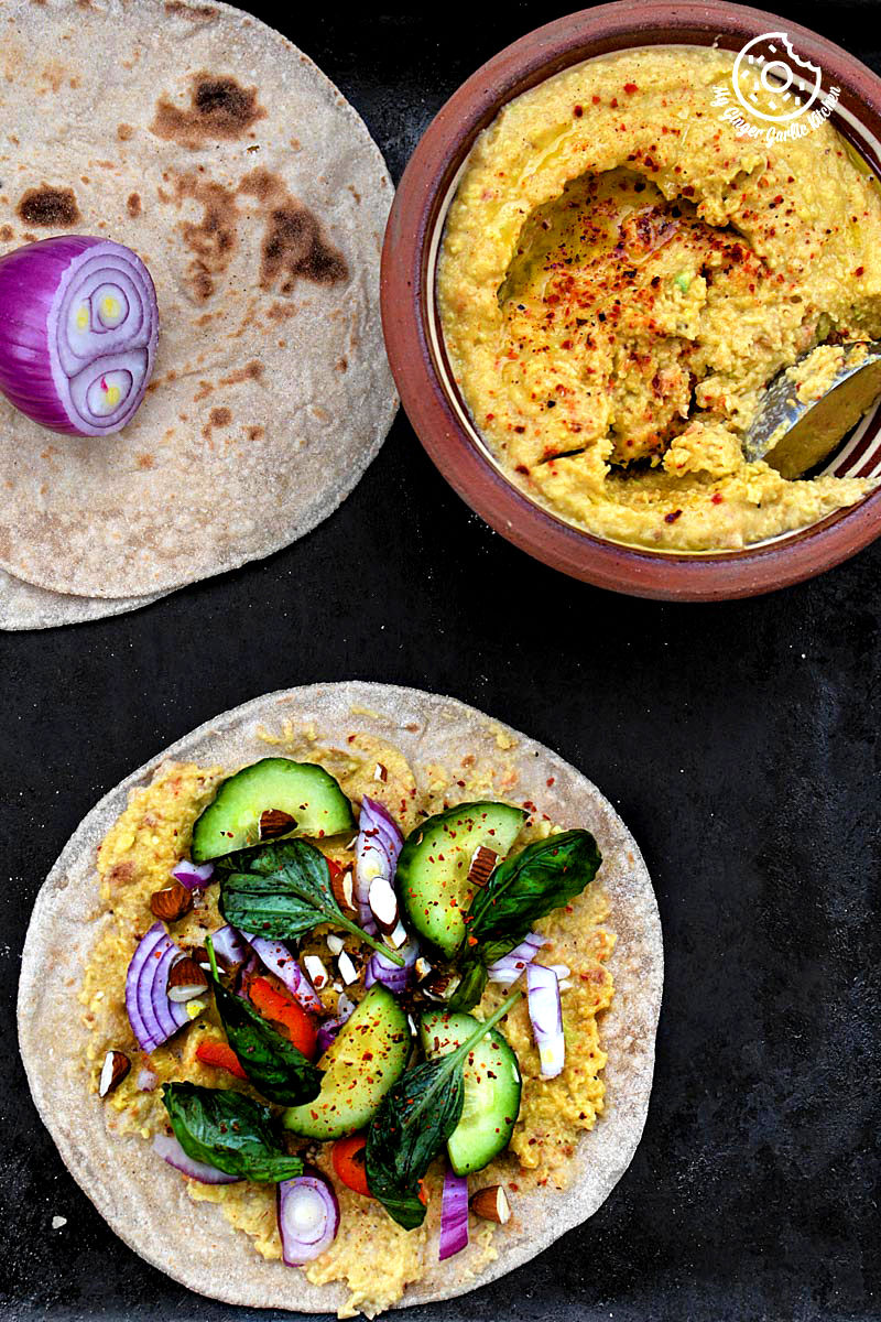 indian chapati with peppery garlicky avocado spread with different toppings and a bowl of avocado spread on a table