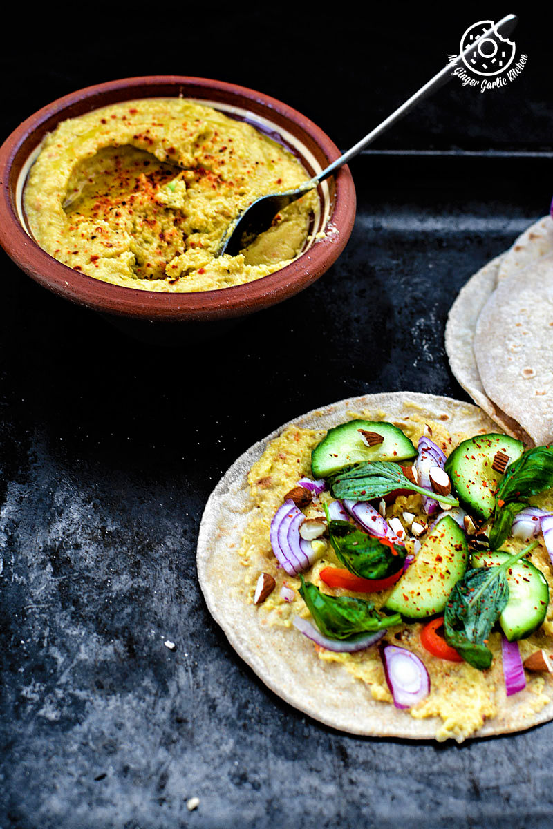 an indian chapati with peppery garlicky avocado spread and a side of garlicky avocado spread with different toppings on a tray