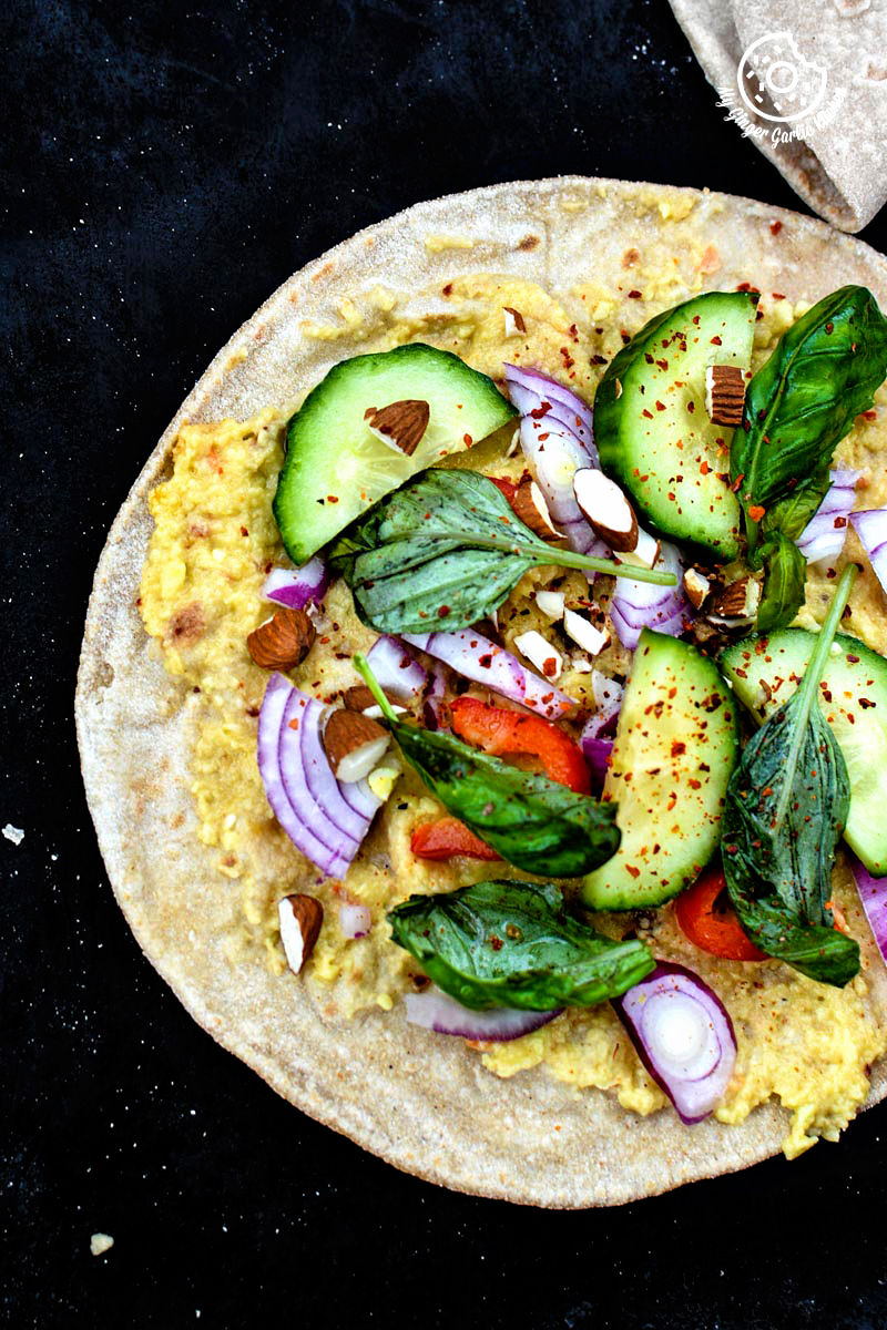 an indian chapati with peppery garlicky avocado spread and other ingredients on it
