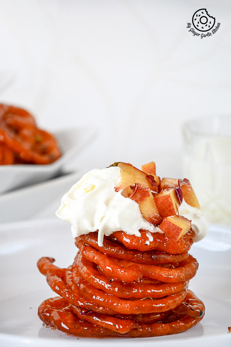 a stack of instant peach jalebis with whipped cream and peaches on top