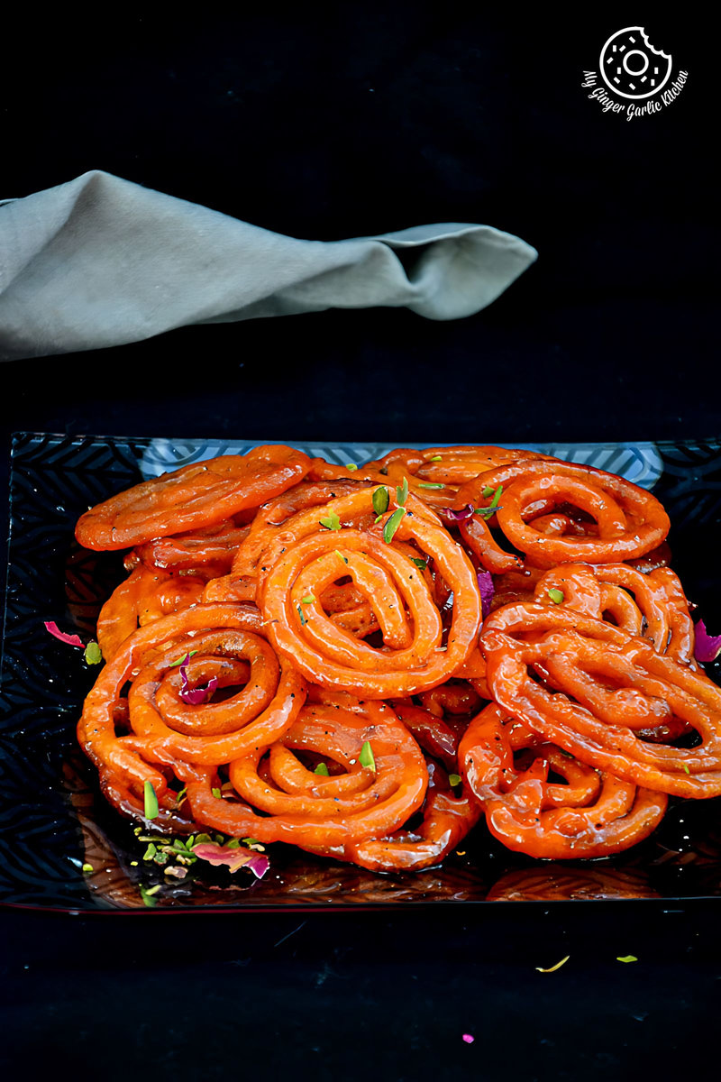 a plate of instant peach jalebis with pistachios on it