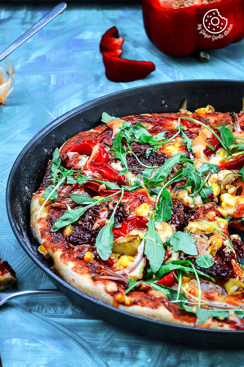 a pizza with pepper corn arugula pizza with sun dried tomatoes on it in a pan