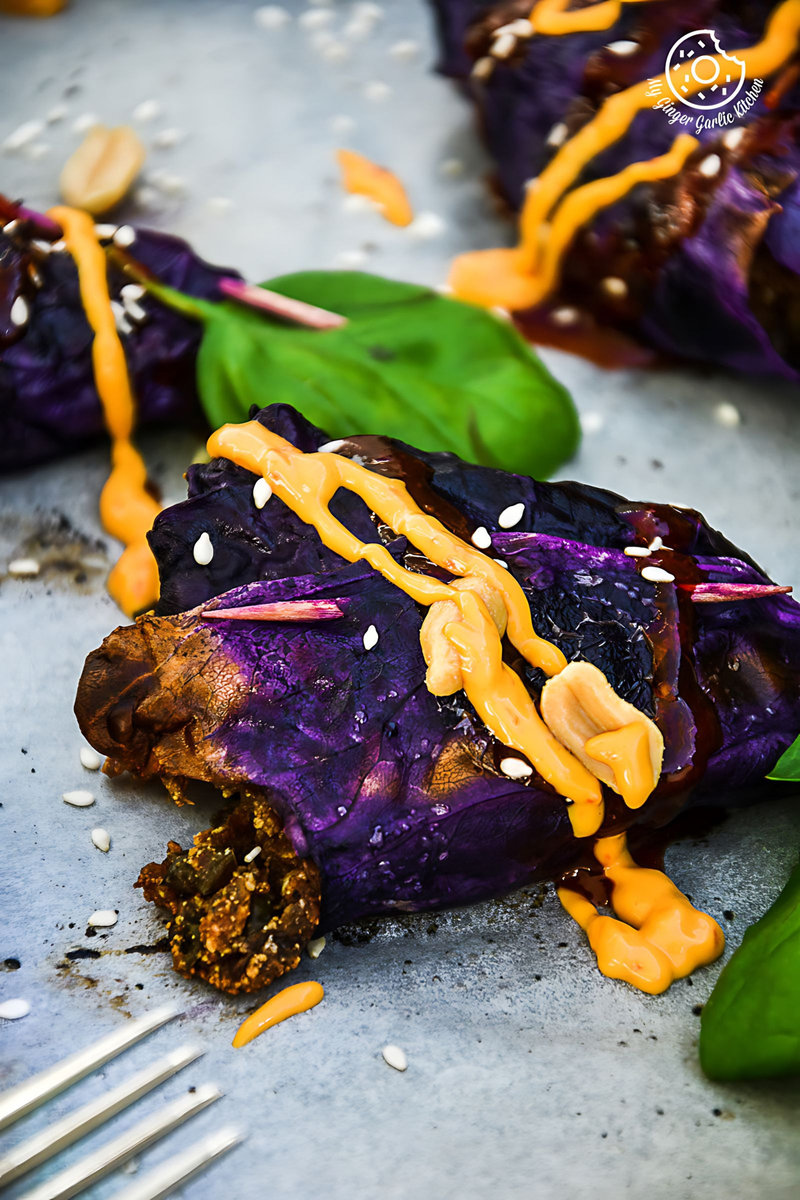 potato panner stuffed roasted red cabbage cones with peanuts, sauce and a fork on a table