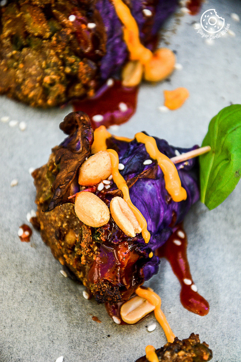 potato panner stuffed roasted red cabbage cone on a plate with sauce and nuts
