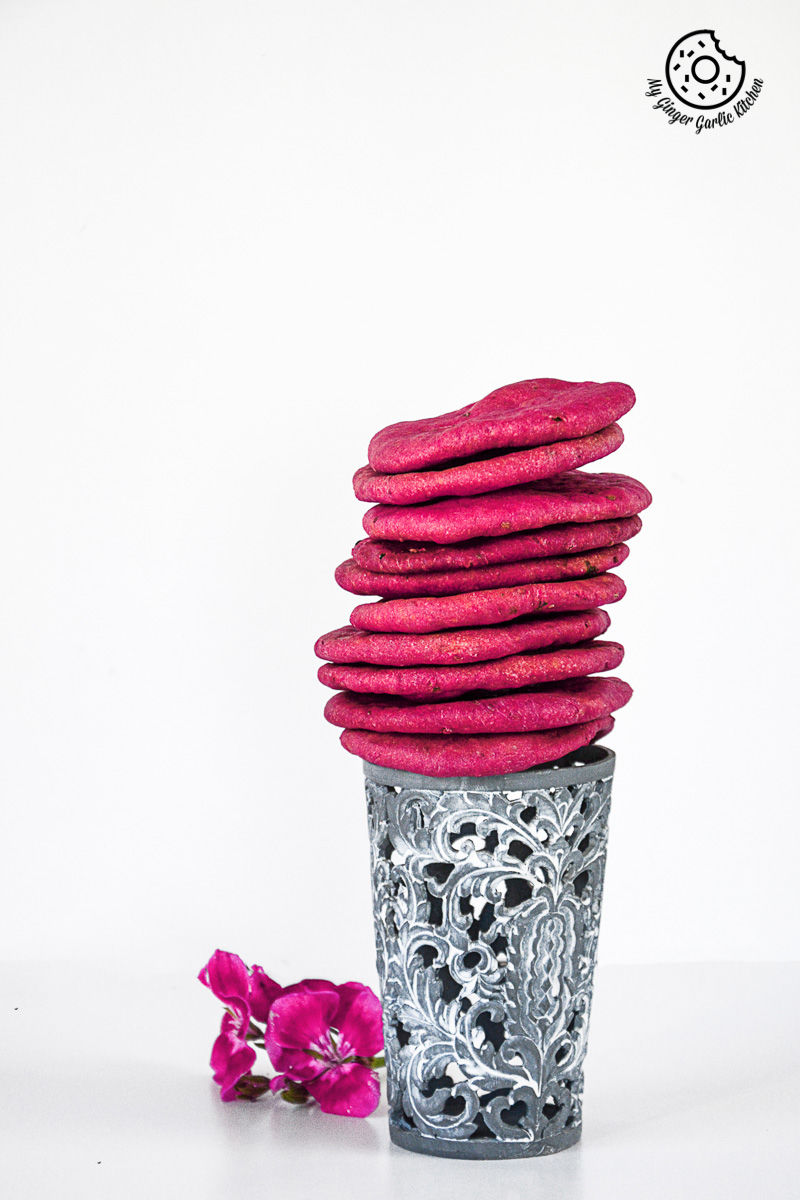 a stack of pink baked beet mathri sitting on top of a glass