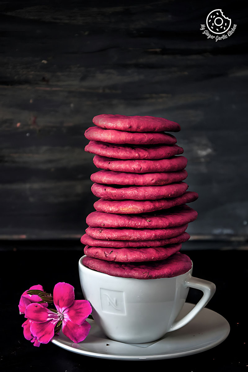 a stack of pink baked beet mathri sitting on a plate in a cup