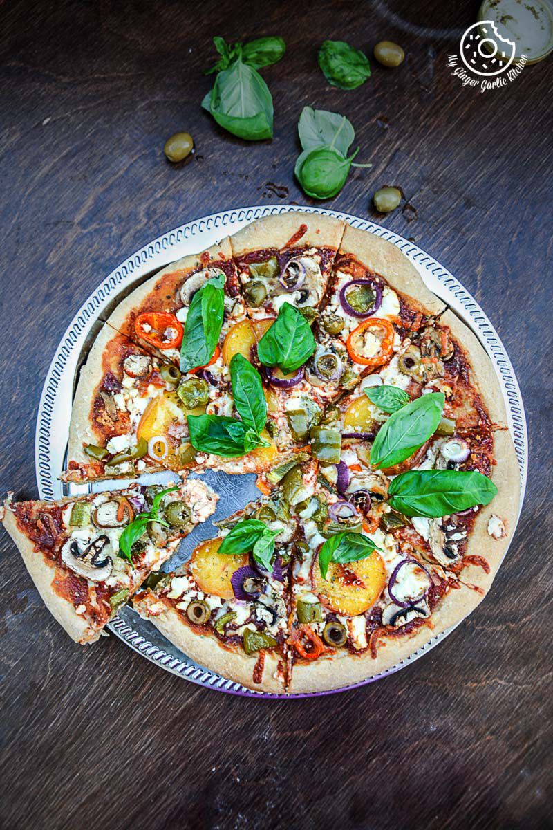 a wholewheat peach mushroom pizza with feta and fresh basil with many toppings on a plate