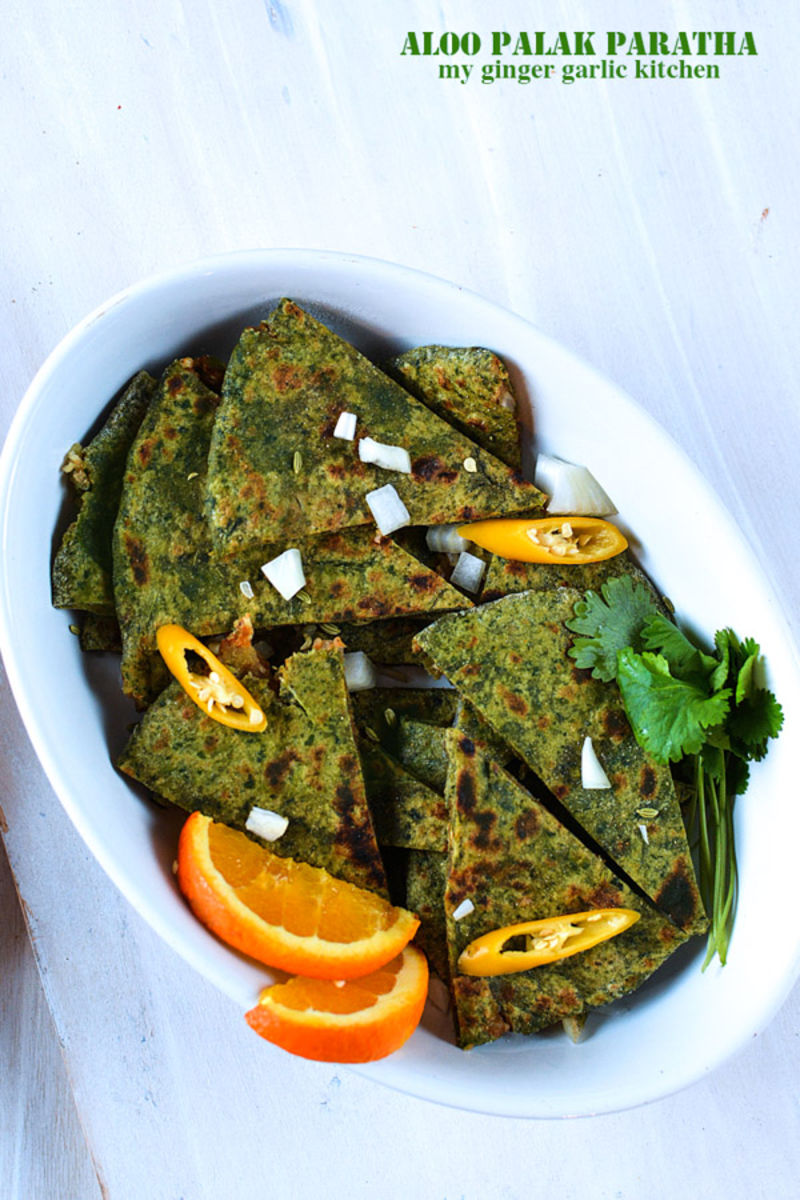 a plate of aloo palak paratha slices with orange slices