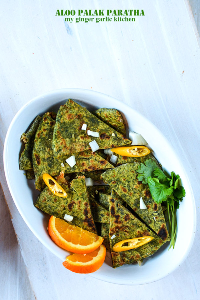 a plate of aloo palak paratha slices with orange slices
