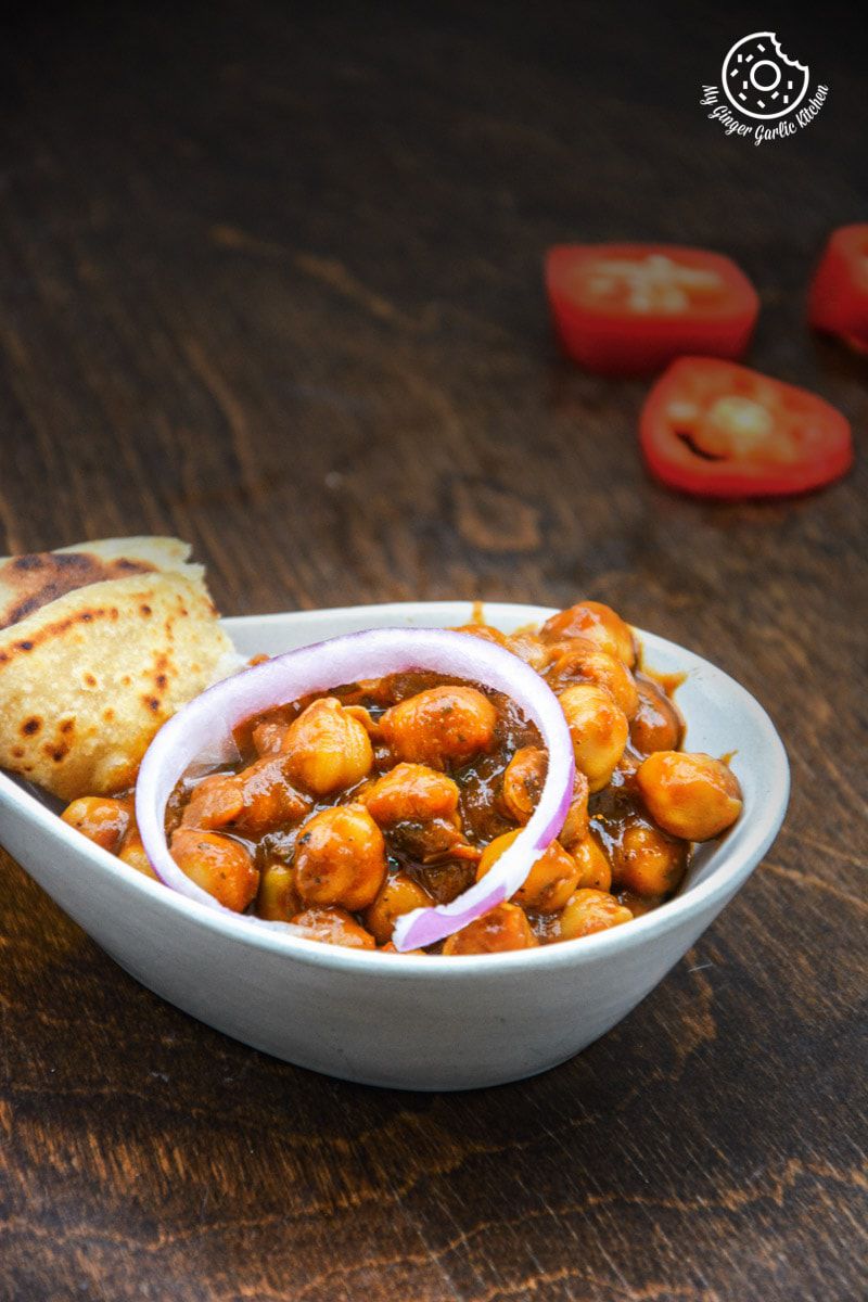 a bowl of amritsari chole with onions and flatbread
