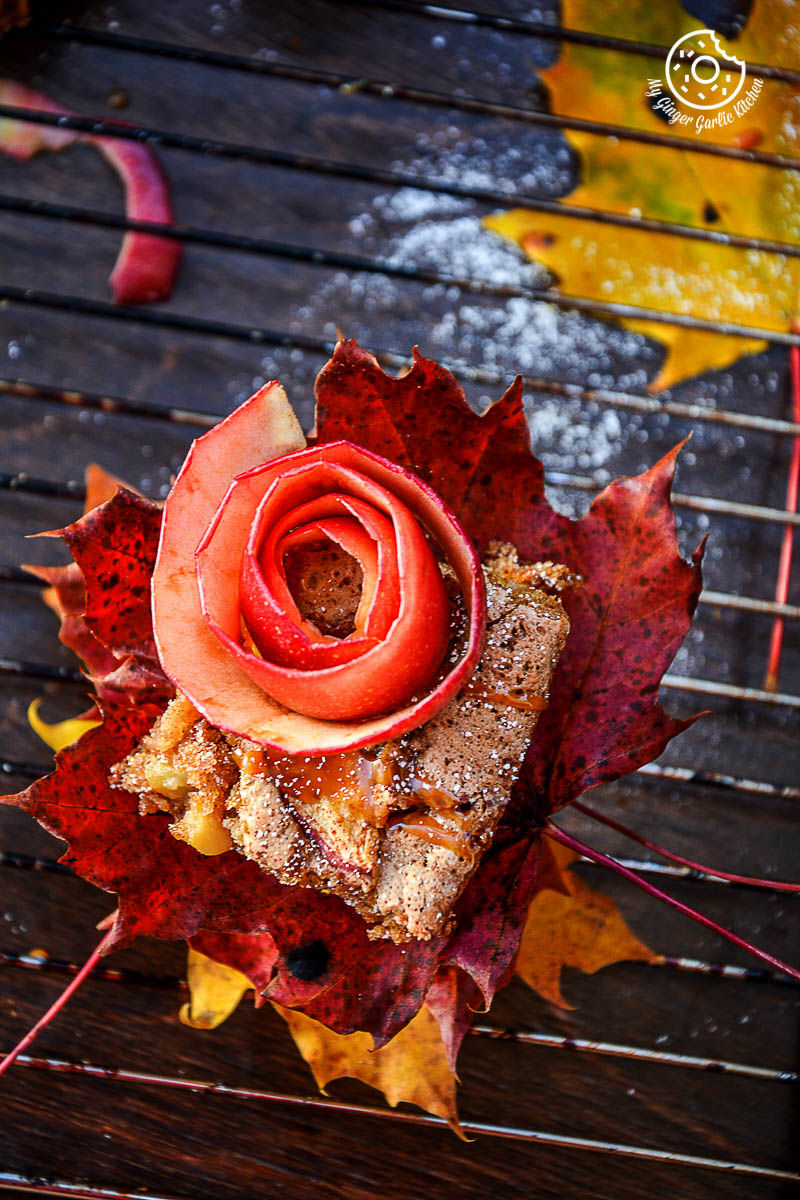 a apple cinnamon brownie topped with rose on a leaf on a bench in the fall