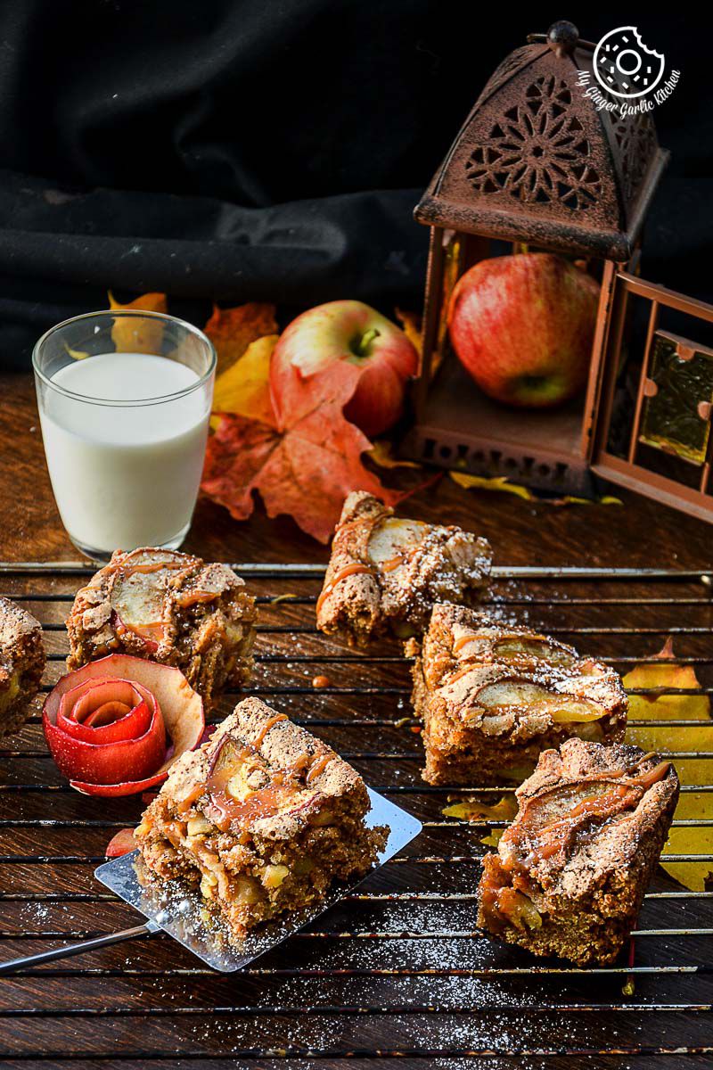 several pieces of apple cinnamon brownie with caramel drizzle on a cooling rack with a glass of milk