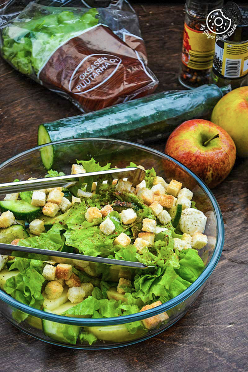 a salad with lettuce, apples, and croutons in a bowl