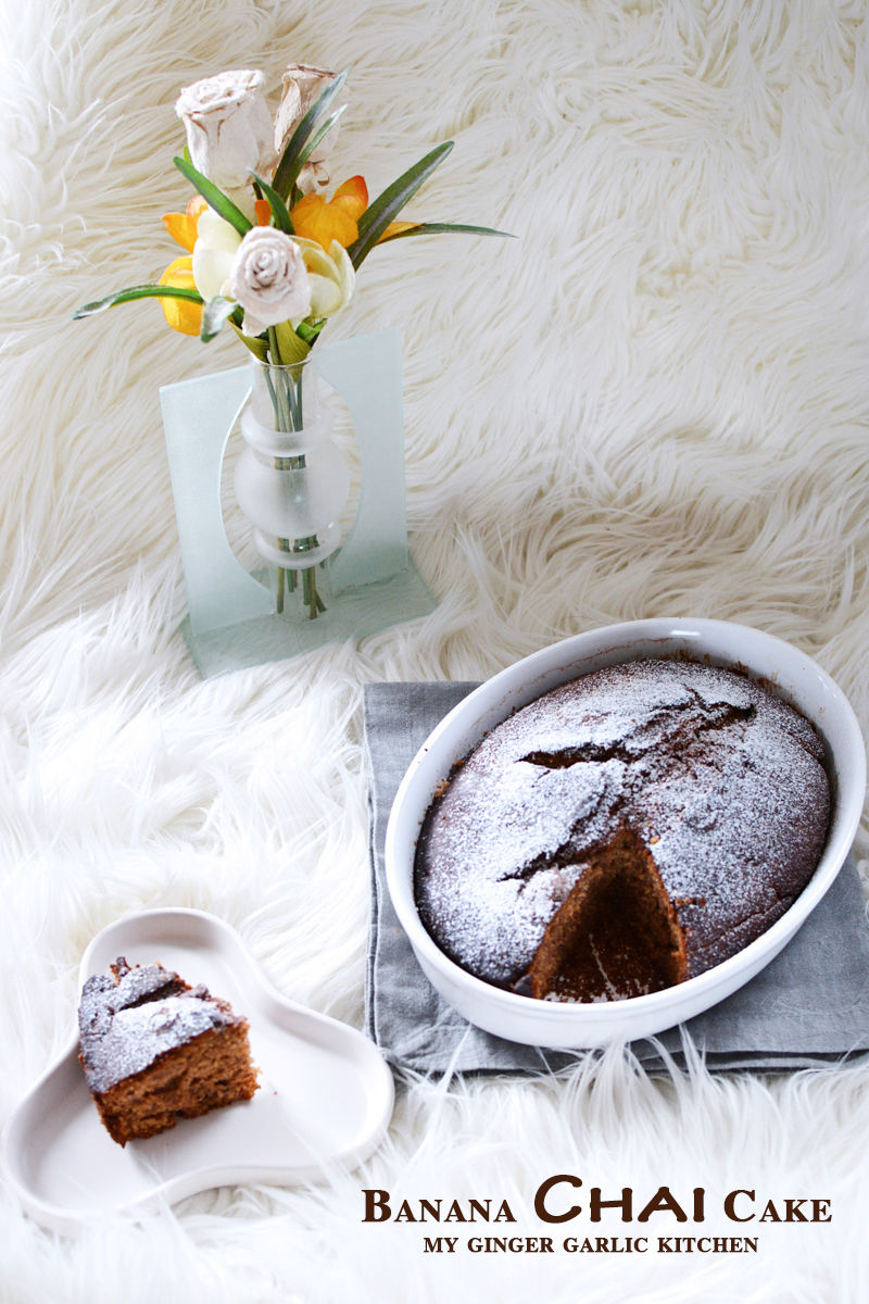 banana chai cake in a bowl on a plate next to a vase of flowers