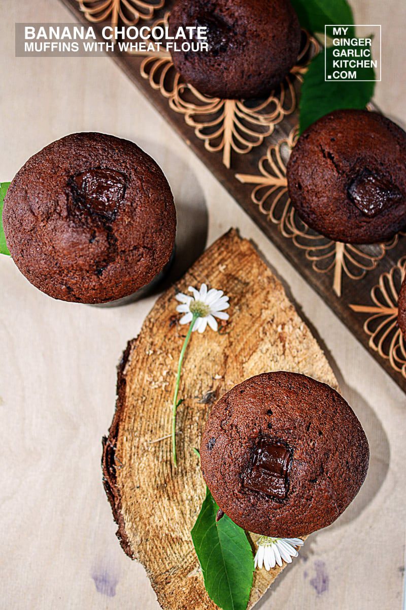three banana chocolate muffins on a wooden board with a flower